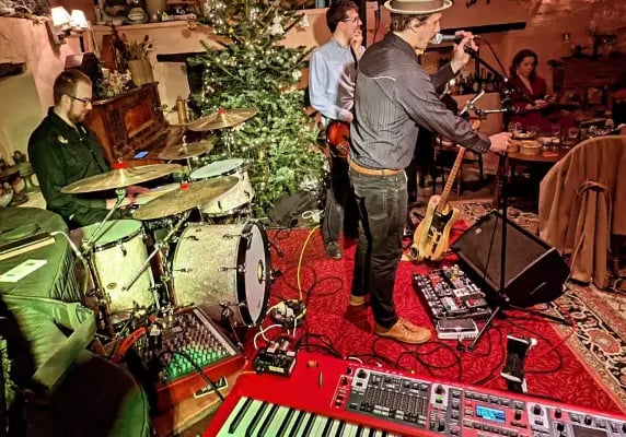 The full 4-piece Mosaic band performing live in a rustic barn venue with professional lighting