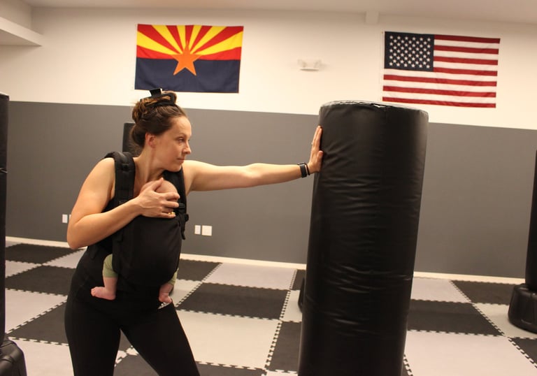 Instructor carrying baby and striking heavy bag