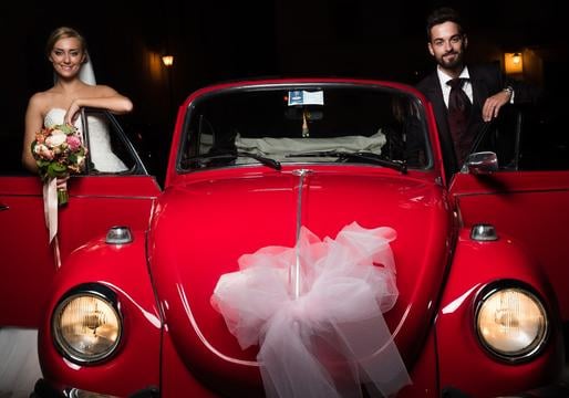 Sposi nel loro giorno da sogno che scattano una foto con il nostro splendido maggiolone d'epoca.