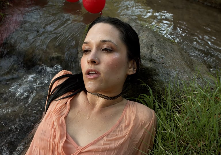 a woman in a pink shirt is laying in water in a music video
