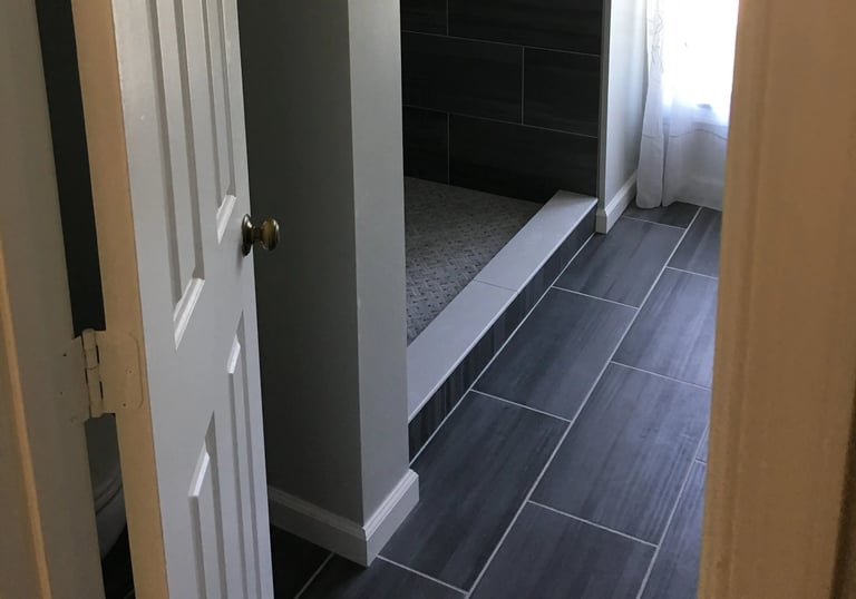 Modern bathroom with walk-in shower, dark gray floor tiles, and light gray walls
