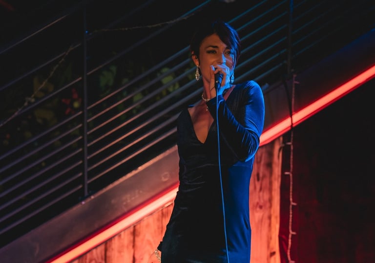 Jessie BaréKa interprète une chanson sur scène en robe noire élégante.