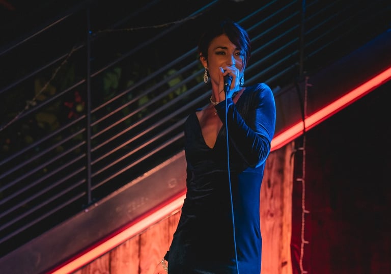 Jessie BaréKa interprète une chanson sur scène en robe noire élégante.
