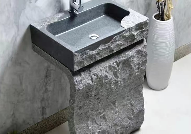 a stone sink with a stone sink and a vase with flowers