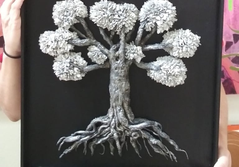 a woman holding a framed picture of a tree