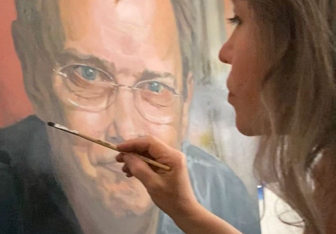 Close up on Stefanie painting on a large oil portrait.