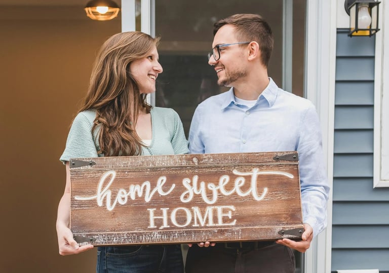 Happy homeowners with home sweet home sign, representing the excitement of first-time home buyers