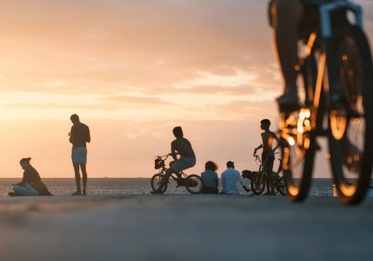 People enjoying the sunset at the beach in Mauritius, with silhouettes of bikers in the foreground.