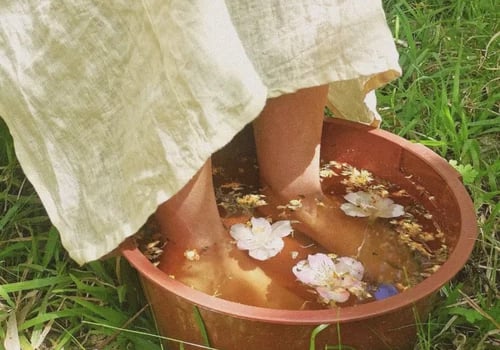 pies de mujer en recipiente con agua floral