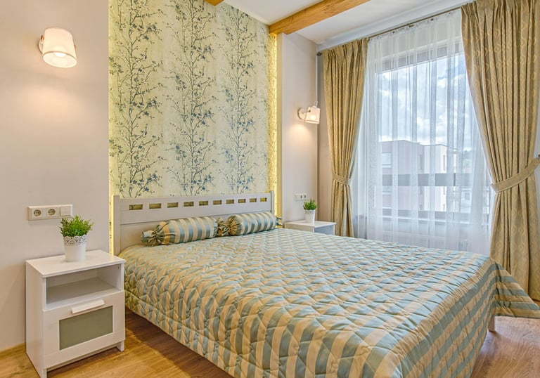 Modänes Hotelzimmer mit schickem Interieur einem Bett, Beistelltisch und hellen Vorhängen