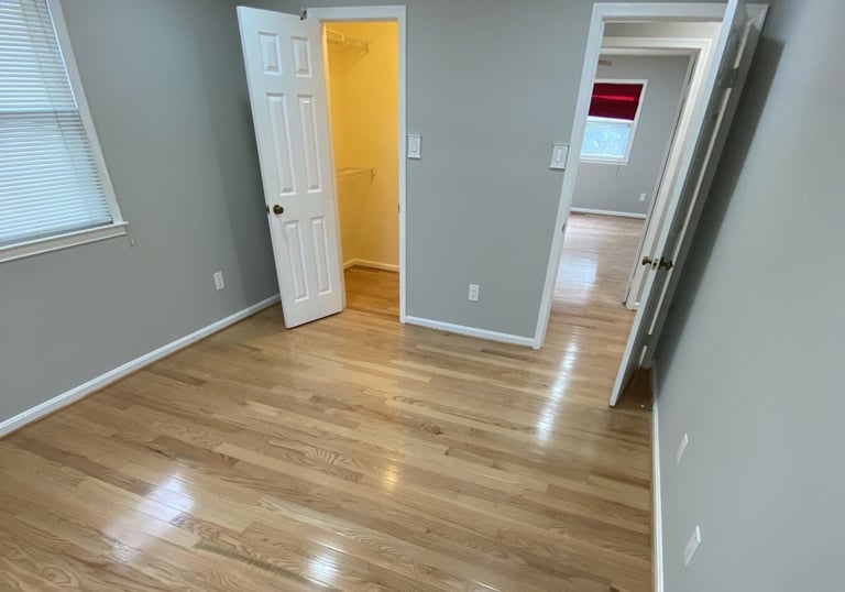 Bedroom with closet doors, smooth hardwood floors, and neutral paint