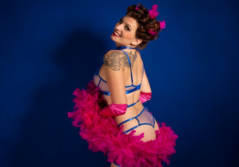 Pin up joyeuse en lingerie bleue avec un boa en plumes rose, qui sourie.