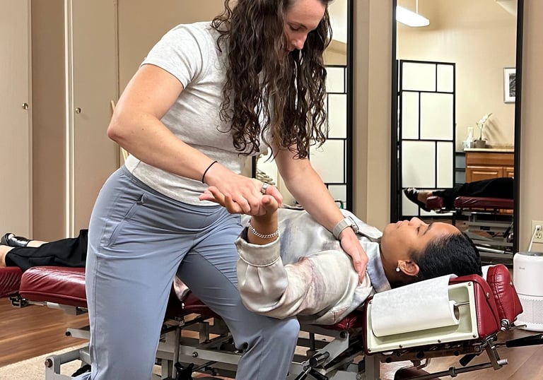 Chiropractor performing nerve tension test of arm with patient laying on back on chiro table.