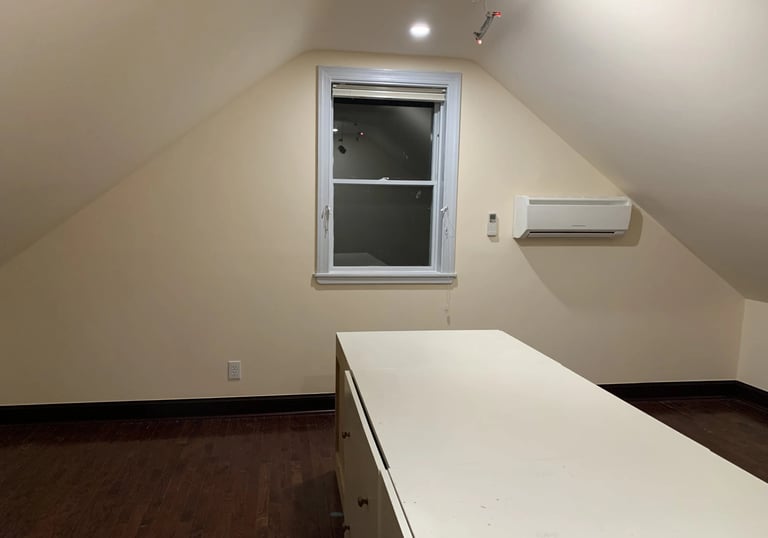 Attic room with sloped ceilings, hardwood floor, window, mini-split AC, and storage cabinet