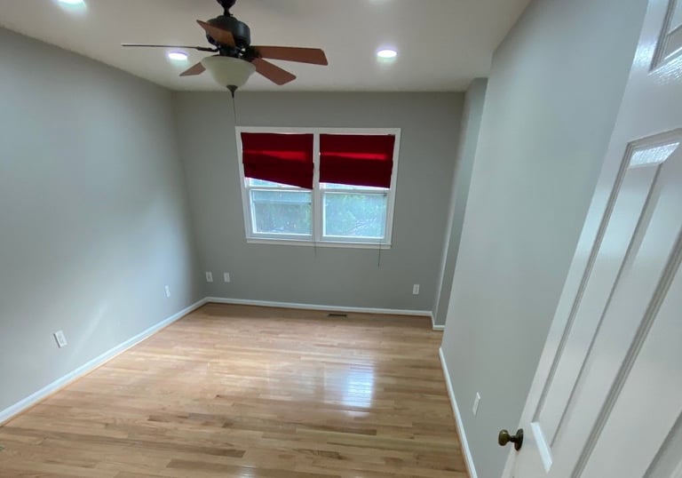 Bedroom with ceiling fan, red shades, and glossy hardwood floorboards