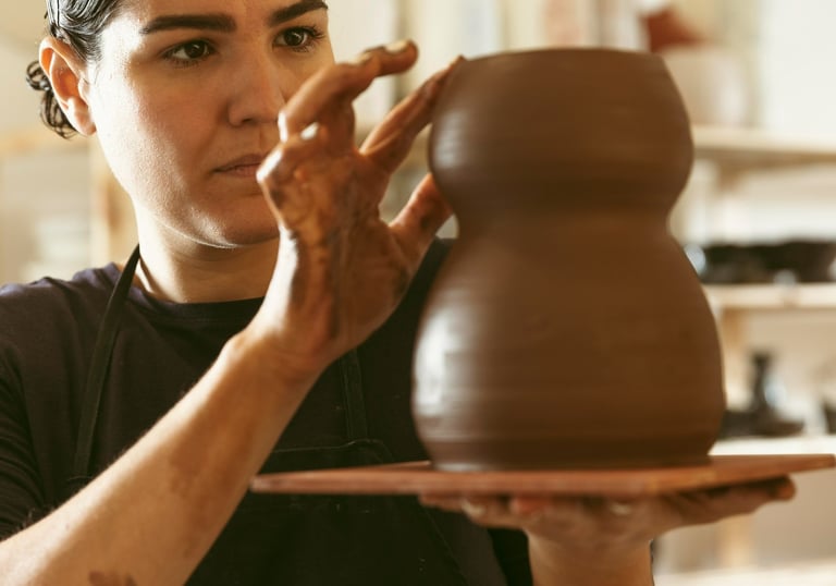 mulher esculpindo vaso em argila