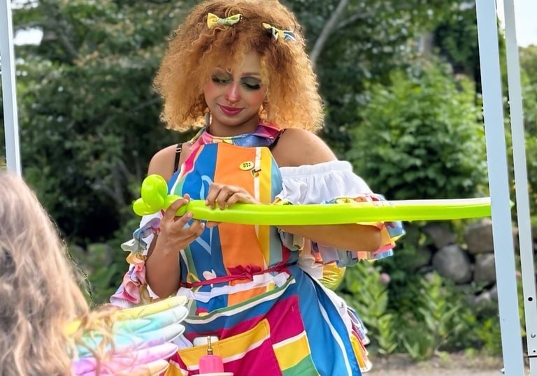 Balloon twister dressed in rainbow making a new shape