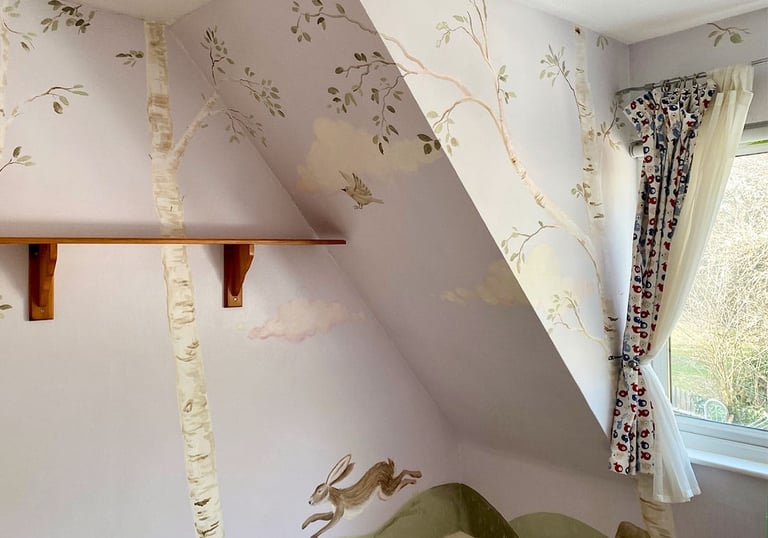 Wide angle on a wrap-around kid’s mural with a painted birch grove and a hare jumping on green ground.