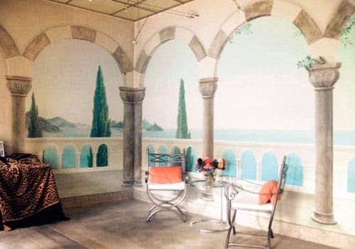 Interior mural with Moorish arches, terrace, cypress trees and ocean view.