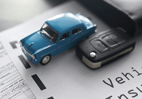 Carro azul de juguete sobre un contrato de compraventa de vehículo usado junto una llave de auto