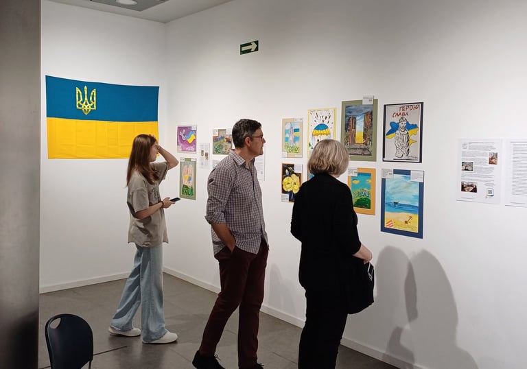 Visitors at the Spanish art gallery with paintings made by kids affected by the war in Ukraine