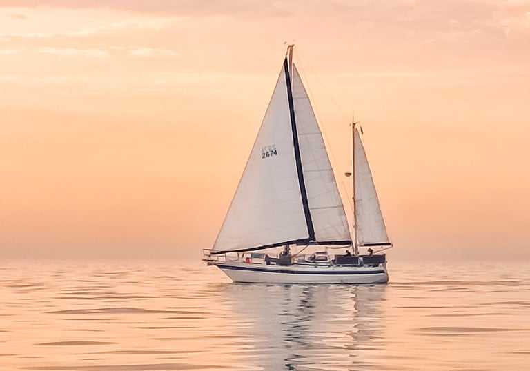 Stahl Ketsch Moana segelt im Sonnenuntergang über das Meer