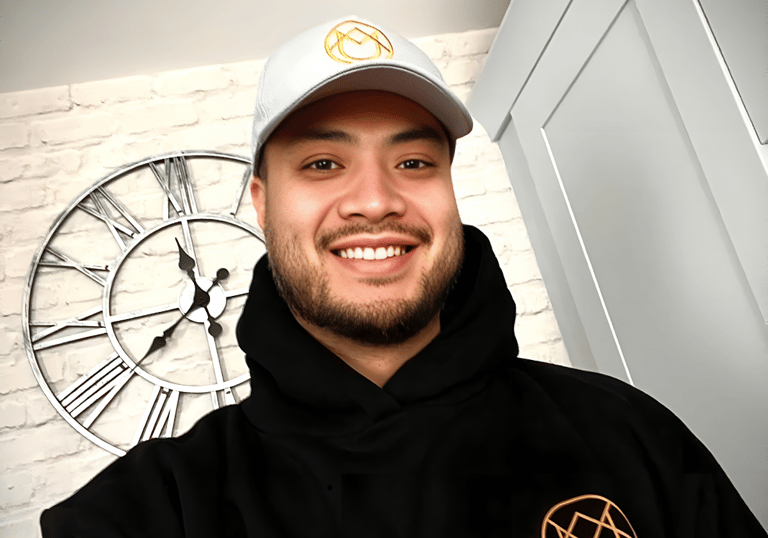 Yau, founder of YAU Barber Studio, smiling in branded hoodie and cap with studio logo, representing professionalism.