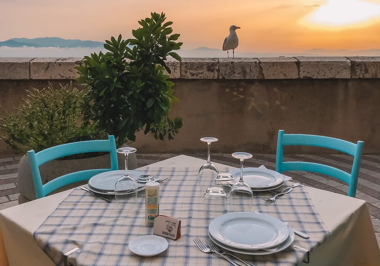 Dinner table on Cagliari bastions at sunset with seagull in background