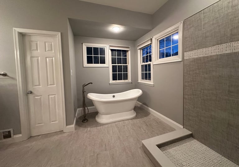 Wide view of renovated bathroom with freestanding bathtub and tiled shower wall