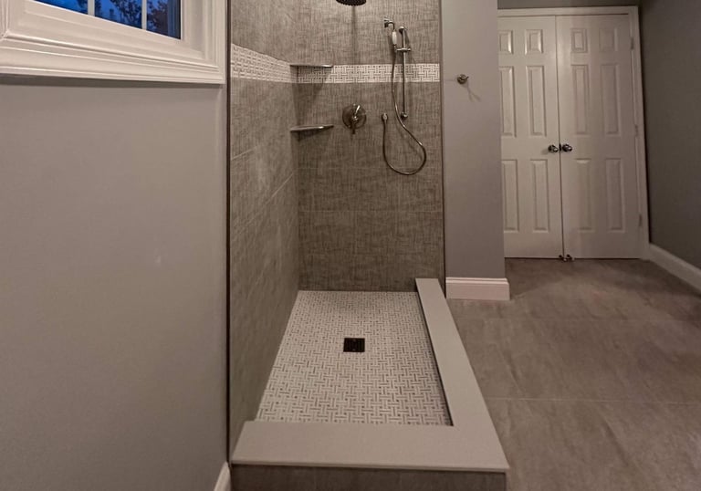 Interior view of glass-enclosed shower with stainless steel fixtures and mosaic tile floor