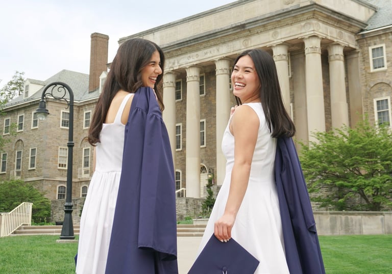 2 graduating seniors walking towards Old Main at Penn State.