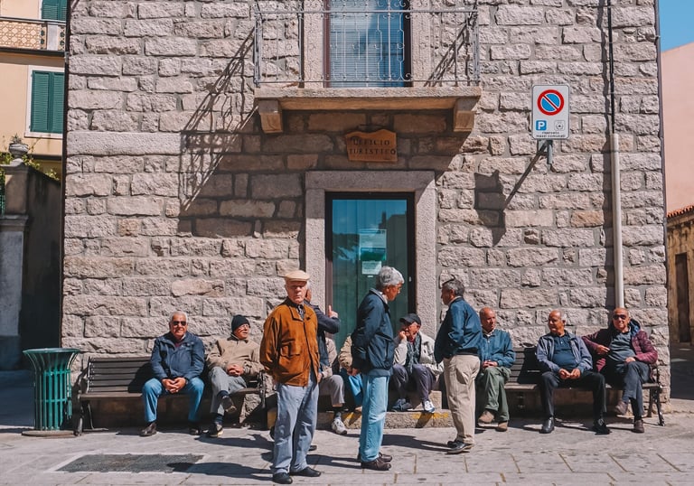 Elderly men chatting in the square of Luras village, Gallura Sardinia