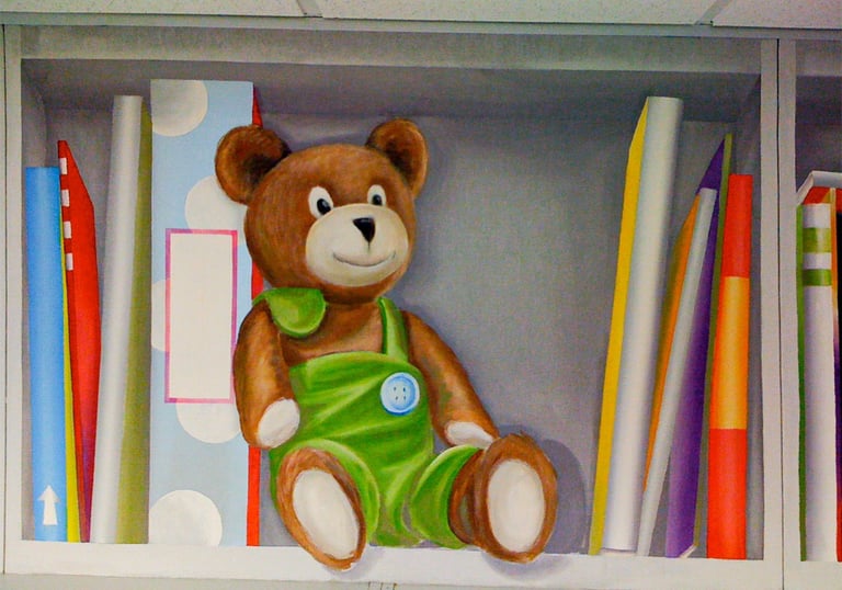 A painted bookshelf in trompe l'oeil style, showing a cute stuffed bear and fun colourful books