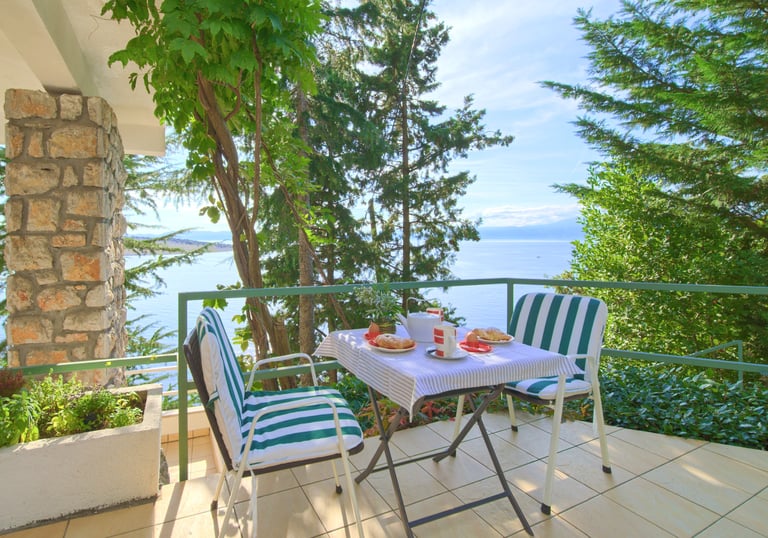 Cozy table and chairs on the apartment terrace with sea and Krk Island views