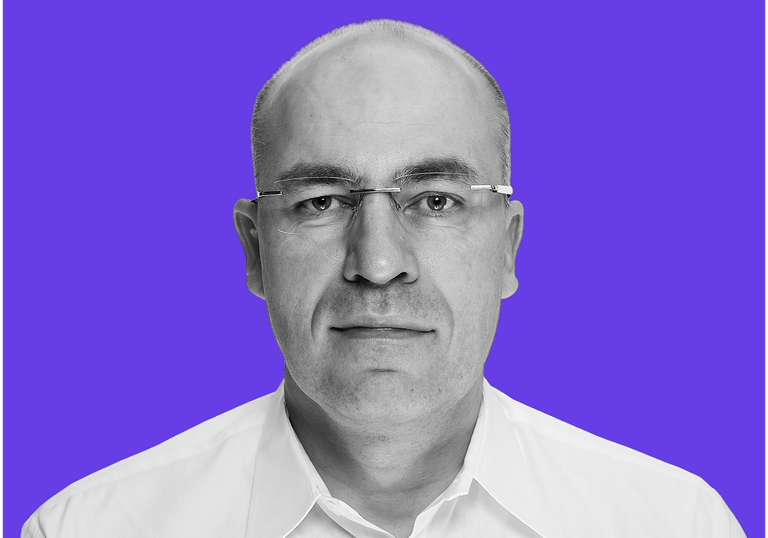 Black and white professional headshot of Detlef Koch on a vibrant purple background.