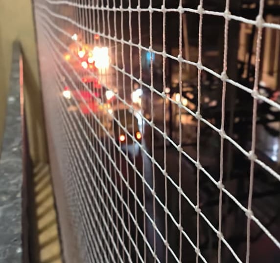 Close-up of a clean, well-maintained balcony safety net with sunlight filtering through.