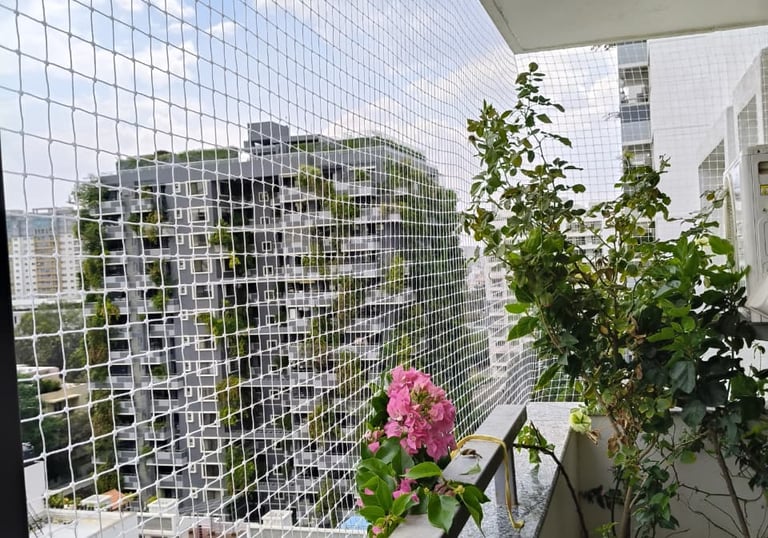 Technician from Sukumari Safety Nets carefully fitting a safety net on a balcony railing, tools in h