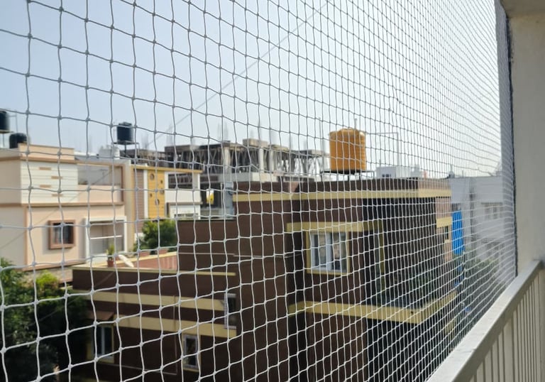 Wide view of a modern balcony wrapped with a sturdy safety net overlooking Electronic City.