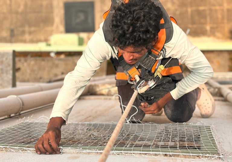 Technician carefully fitting a custom-cut safety net around a complex duct system.