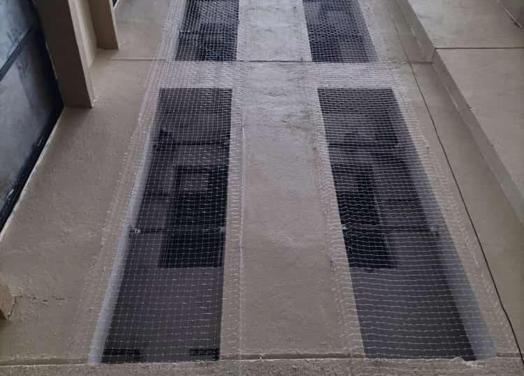 Technician carefully installing a safety net on a balcony in a residential building.