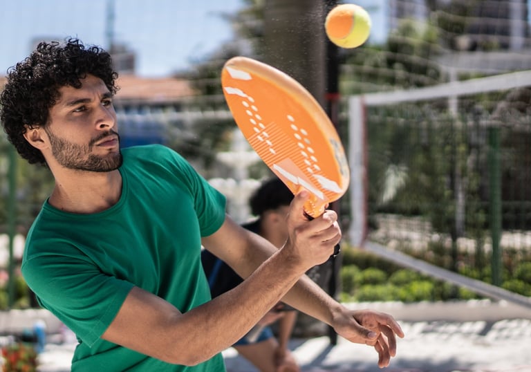 Praticante de beach tennis em movimento de forehand durante treino técnico na areia.