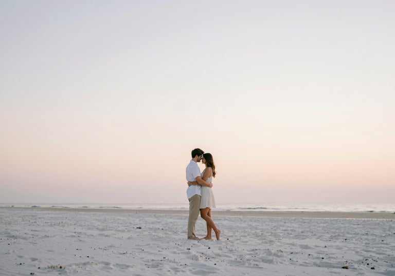 A serene photograph of a couple embracing on a quiet beach in Jacksonville at sunrise. The composition is minimalist and airy, with soft pastel colors in the sky and clean white sand. Refined and elegant style.