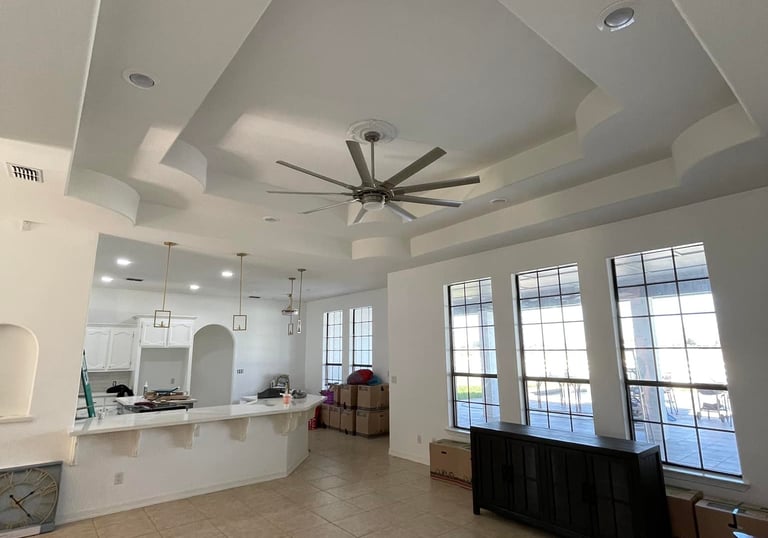 Spacious open concept living room with modern tray ceiling, large windows, and breakfast bar.