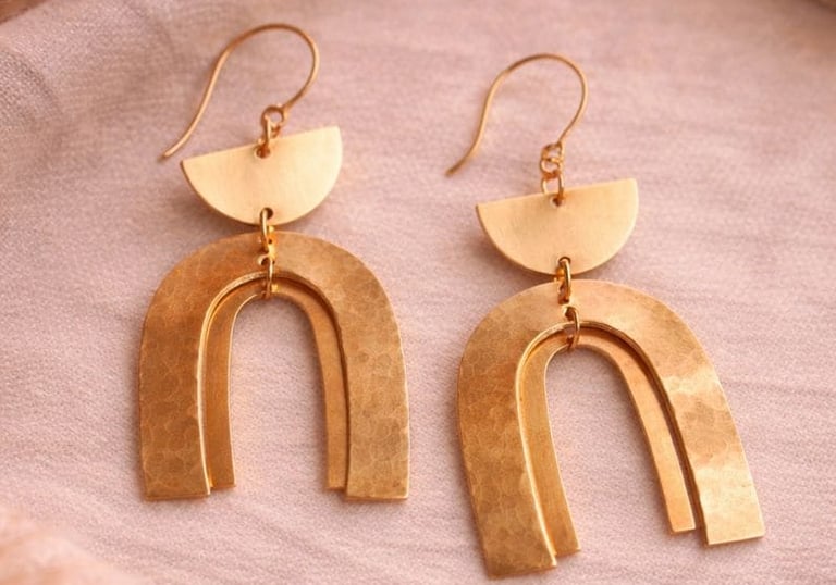 Pendientes de arco dorados hechos a mano con media luna geométrica que cuelga sobre un fon