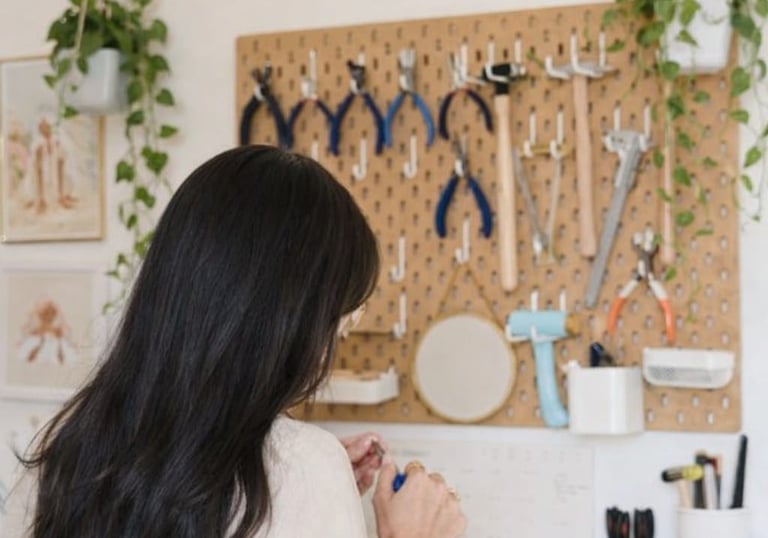 Fabricante de joyas en un banco de trabajo artesanal con herramientas en un tablero de herramientas