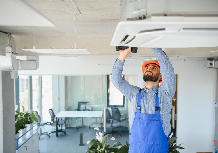 handyman performing maintenance on air conditioning unit in a commercial property in Auckland