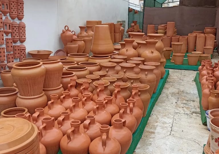 A wide variety of handmade terracotta clay pots, vases, and planters displayed at an outdoor pottery market.