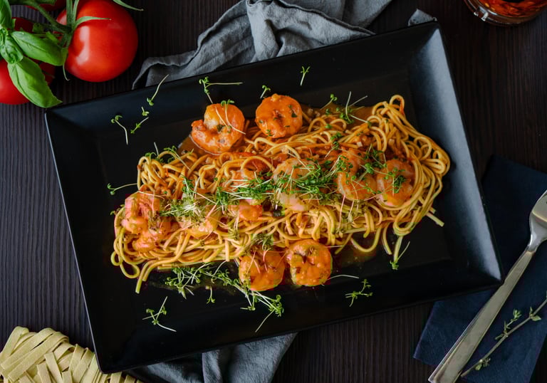 Elegante schwarze Platte mit feinen Spaghetti in einer köstlichen Scampi-Garnelen-Sauce,