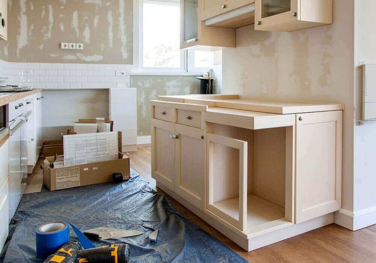 Professional kitchen renovation featuring new wood cabinets, power tools, and white subway tile backsplash installation.