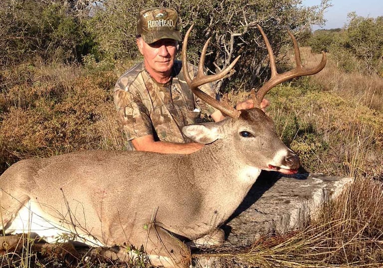 Hunter posing with a large trophy whitetail buck on a Mason County Texas hunting ranch.